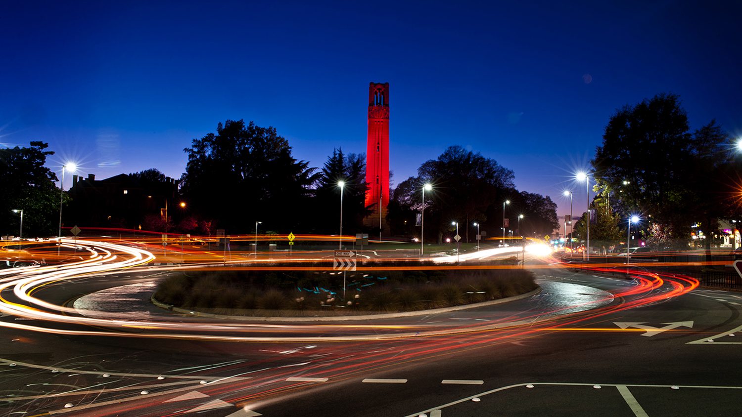 Belltower glowing red at night in traffic