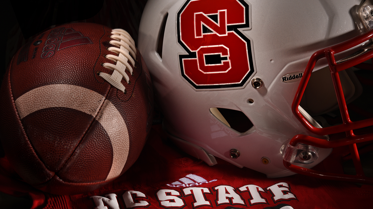 an NC State football helmet next to a football