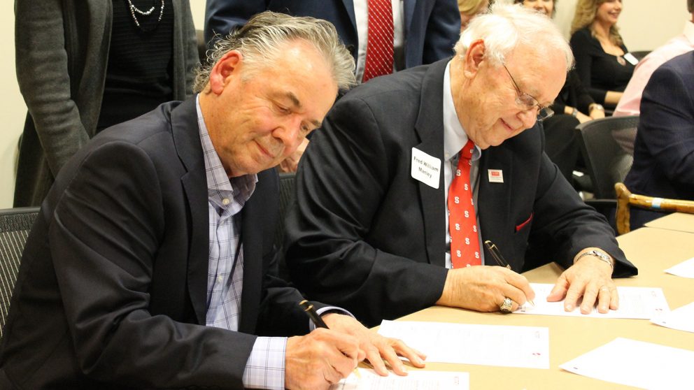 Larry Coats and Fred Manley signing gift agreement