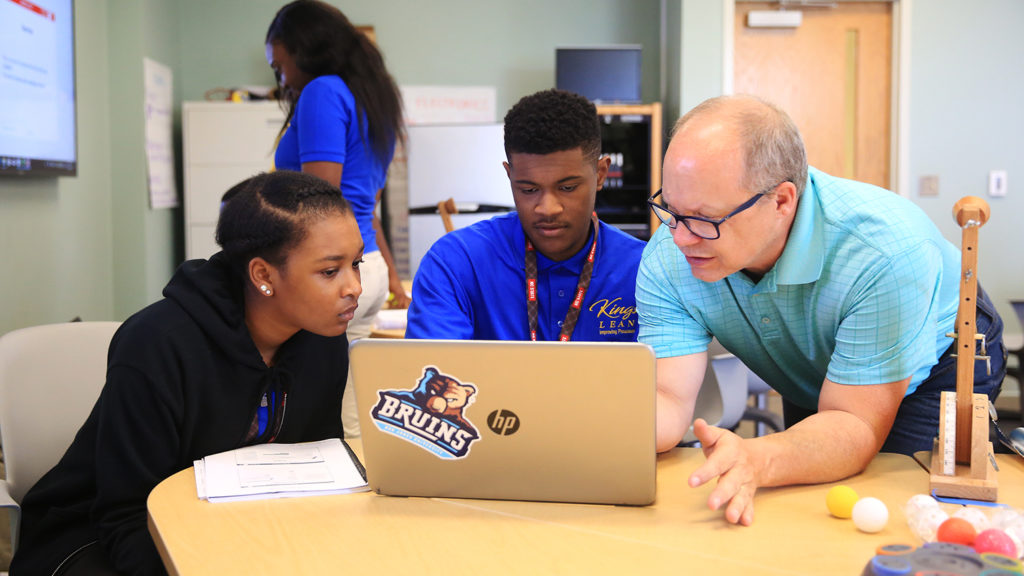 Blessinger advises two students at a laptop