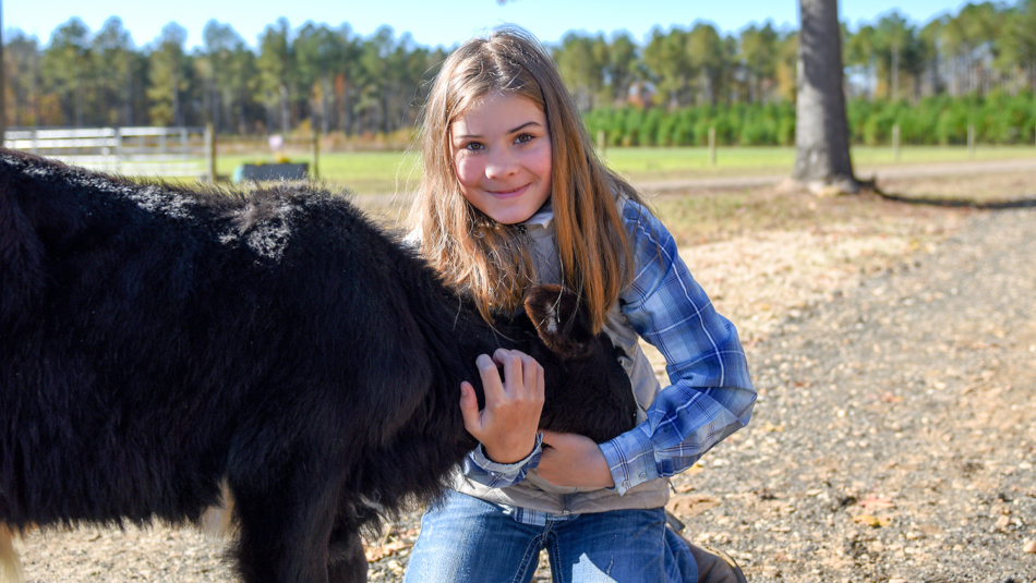 young girl poses with calf