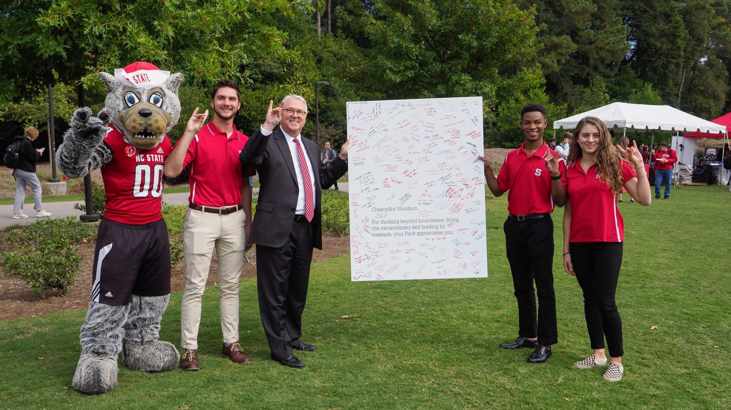 Mr. Wuf, students and Chancellor Woodson hold up a giant Pack Appreciation Card