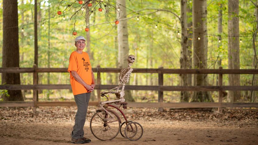 Cindy Stubbs with a skeleton on an old fashioned tricycle in the woods