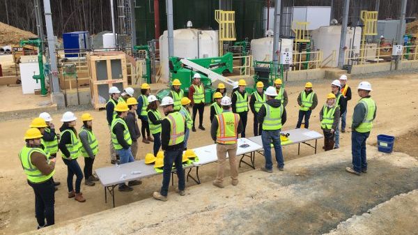students in hard hats and vests being briefed before touring a waste treatment facility