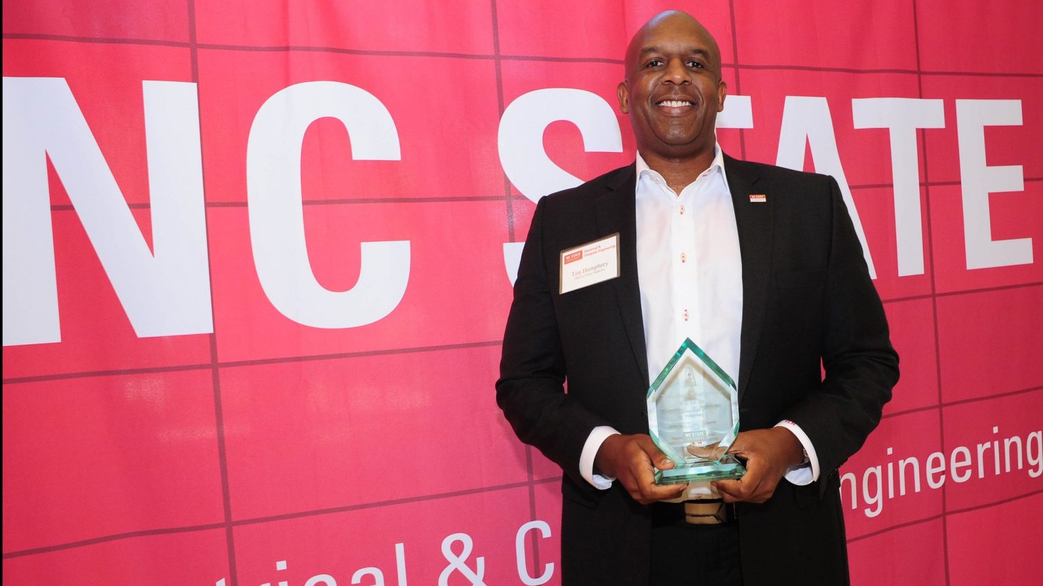 Tim Humphrey holding his Hall of Fame statuette in front of red background