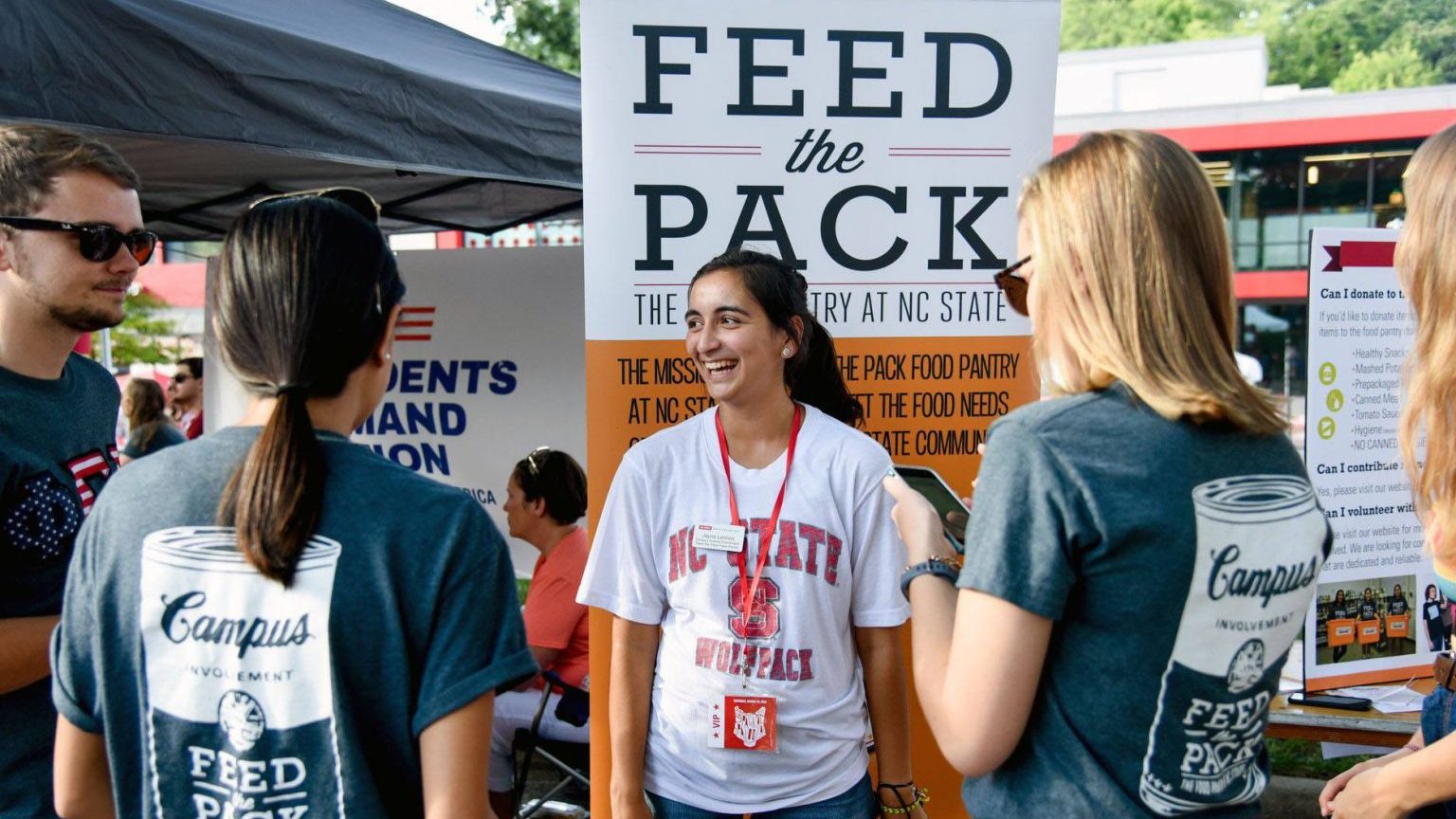 Jayna Lennon standing in front of a Feed the Pack sign