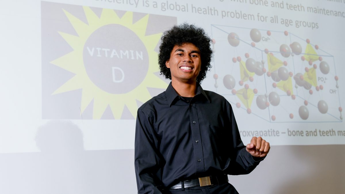 Matthew Warren posing in front of a slide about Vitamin D
