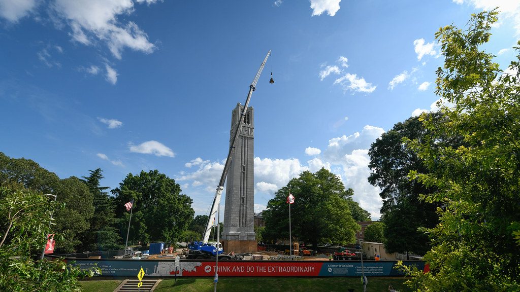 a crane prepares to lower a bell into the belltower