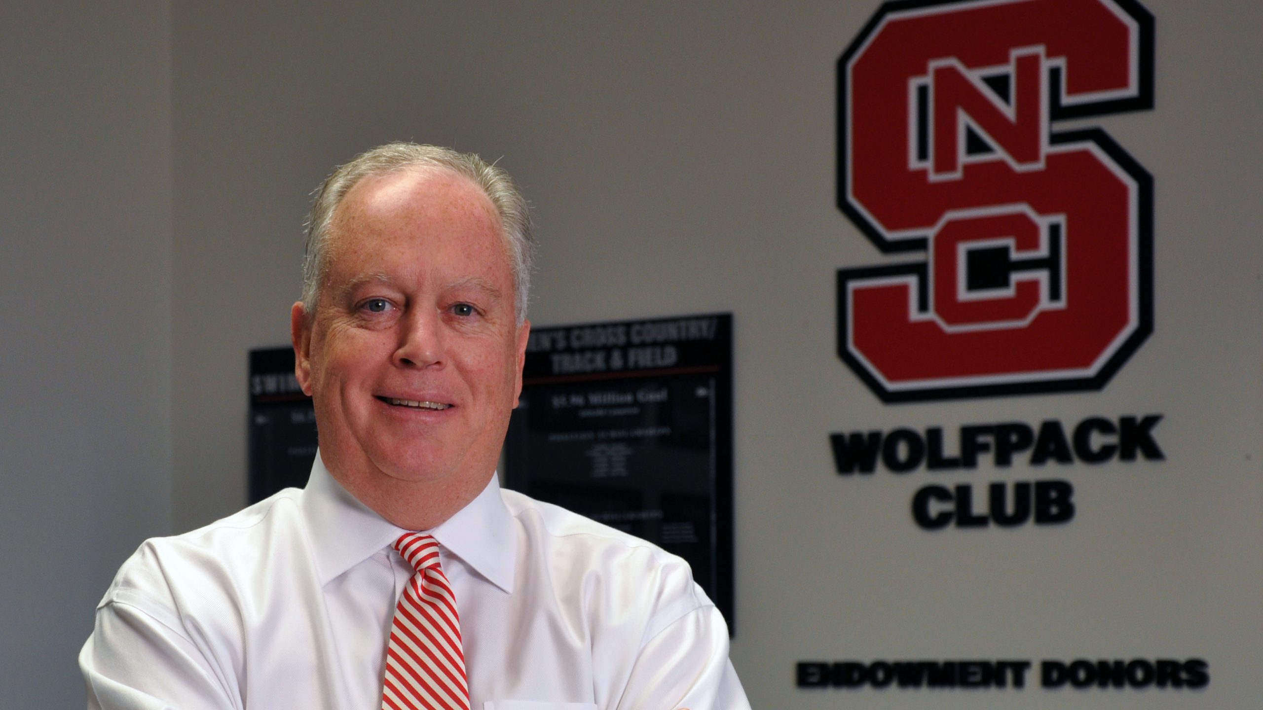 Bobby Purcell posing in front of Wolfpack Club sign