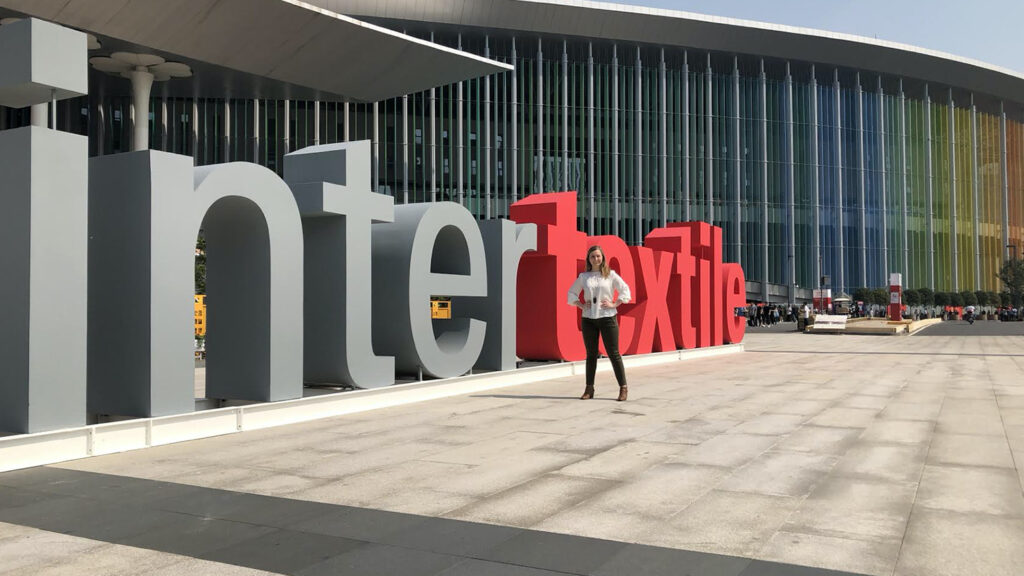 Meredith McKague posing front of giant letters spelling out inter textile