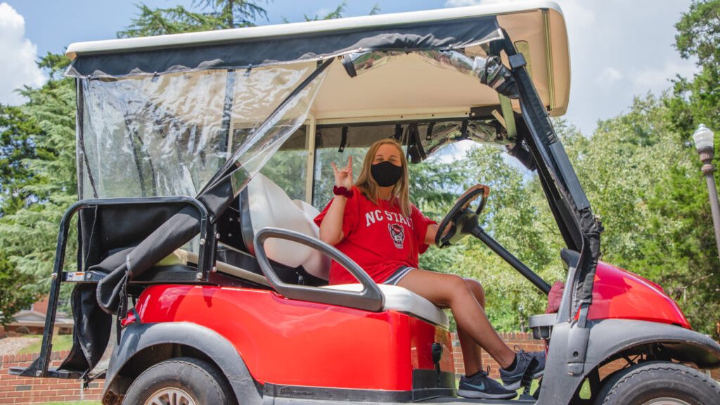 a driver in a face covering does the wolfie in her pickup golf cart