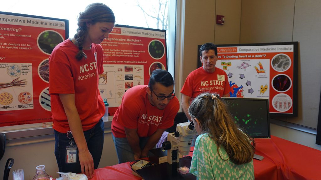Jorge Piedrahita (right) and members of his lab interact at a table at the 2019 College of Veterinary Medicine Open House.