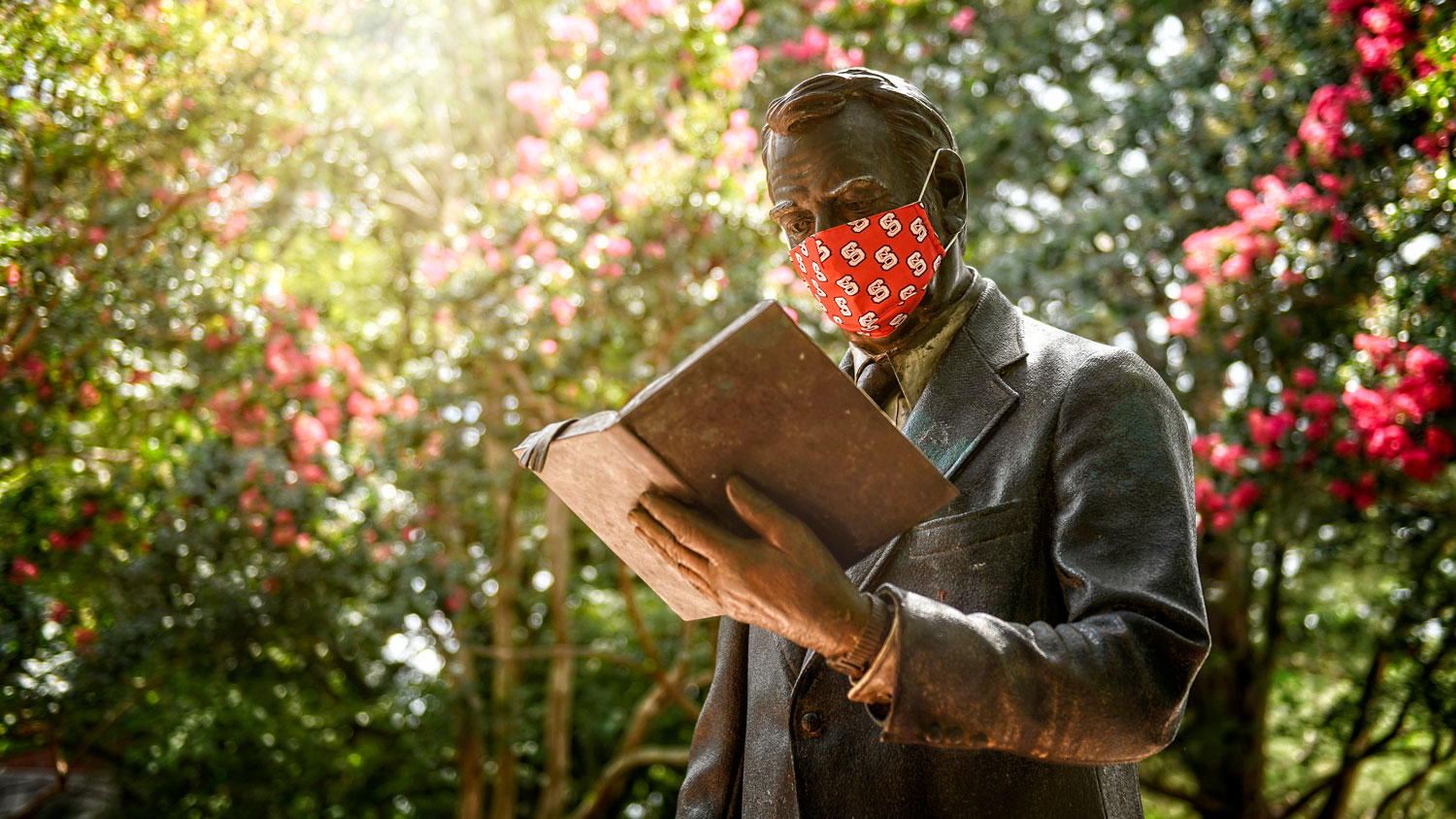the strolling professor statue wearing an NC State face covering