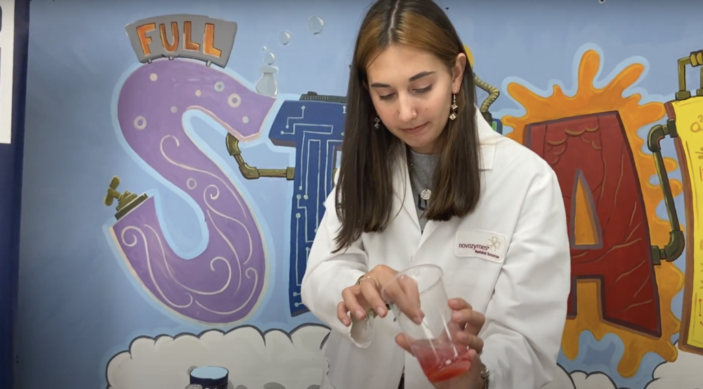 Katelyn Roark in a lab coat demonstrating an experiments for children in the Boys and Girls Club