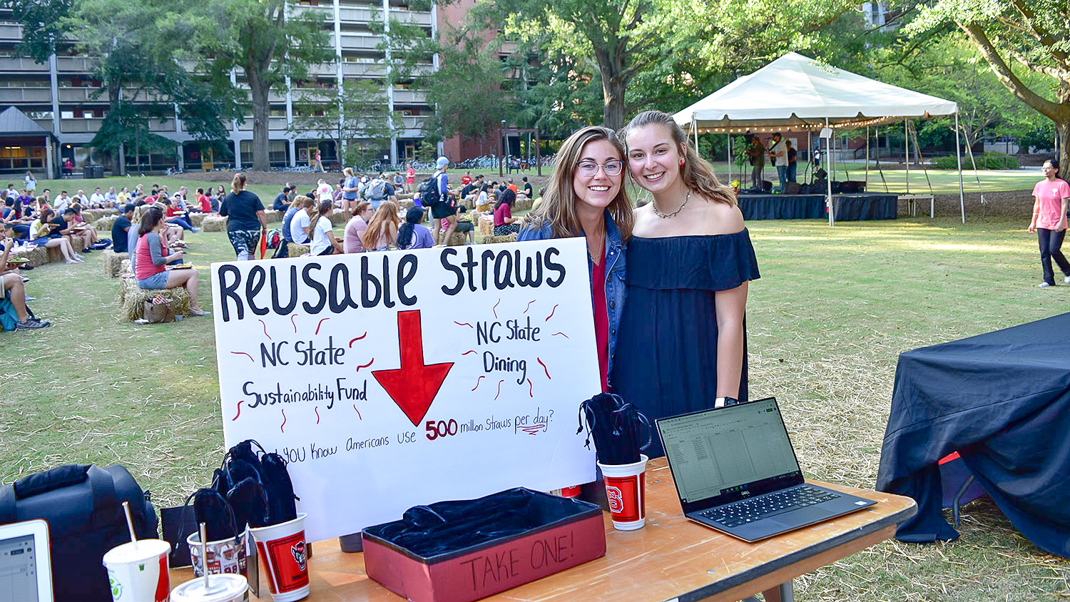Annalise Hafner and Shannon Dolan pose at a table with reusable straw kits at a campus event last year