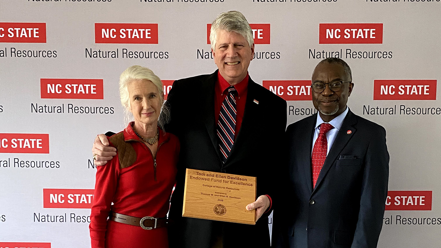 the Davidsons with Dean Myron Floyd in front of a College of Natural Resources banner