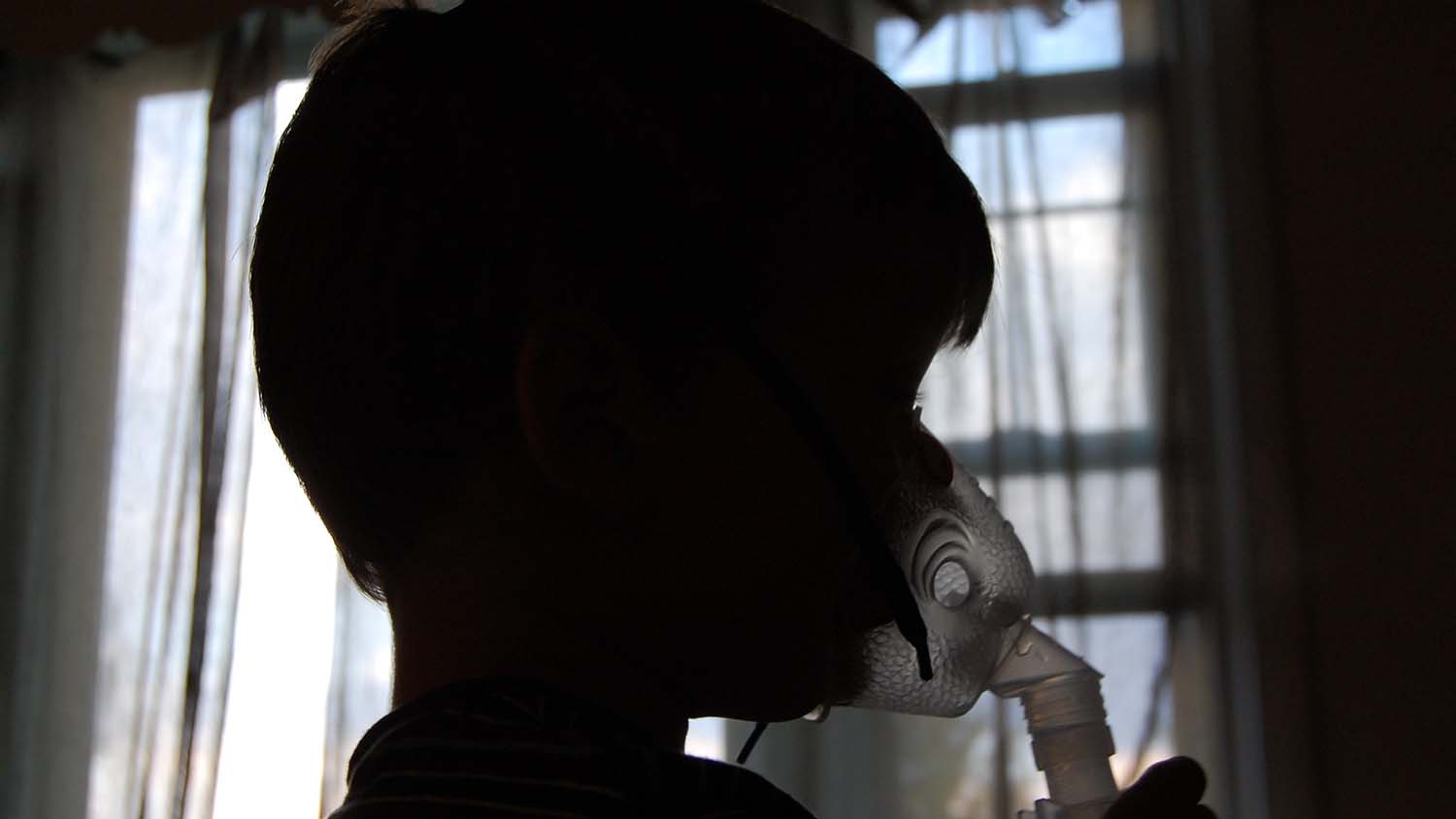 A silhouette of a child with a breathing mask