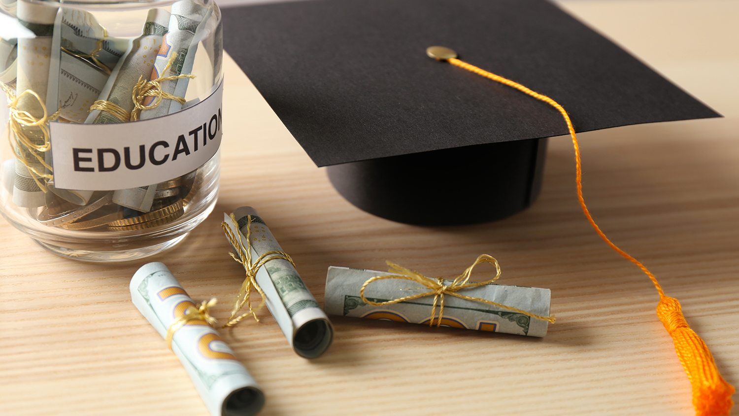 Graduation cap and money saved in a jar for college
