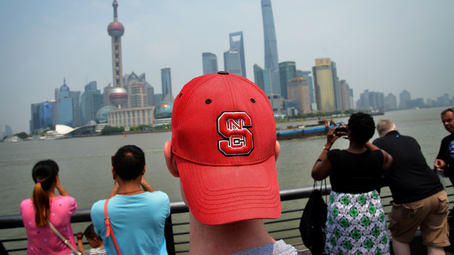 A student wearing an NC State baseball cap on a study-abroad trip