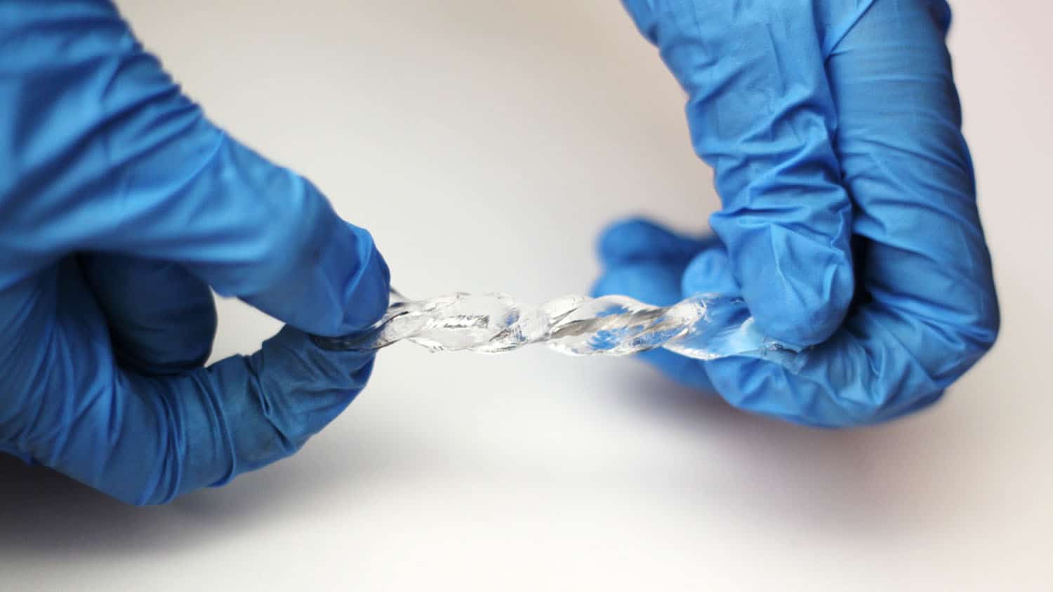 An NC State researcher holding a soft and stretchable device that converts movement into electricity and can work in wet environments.