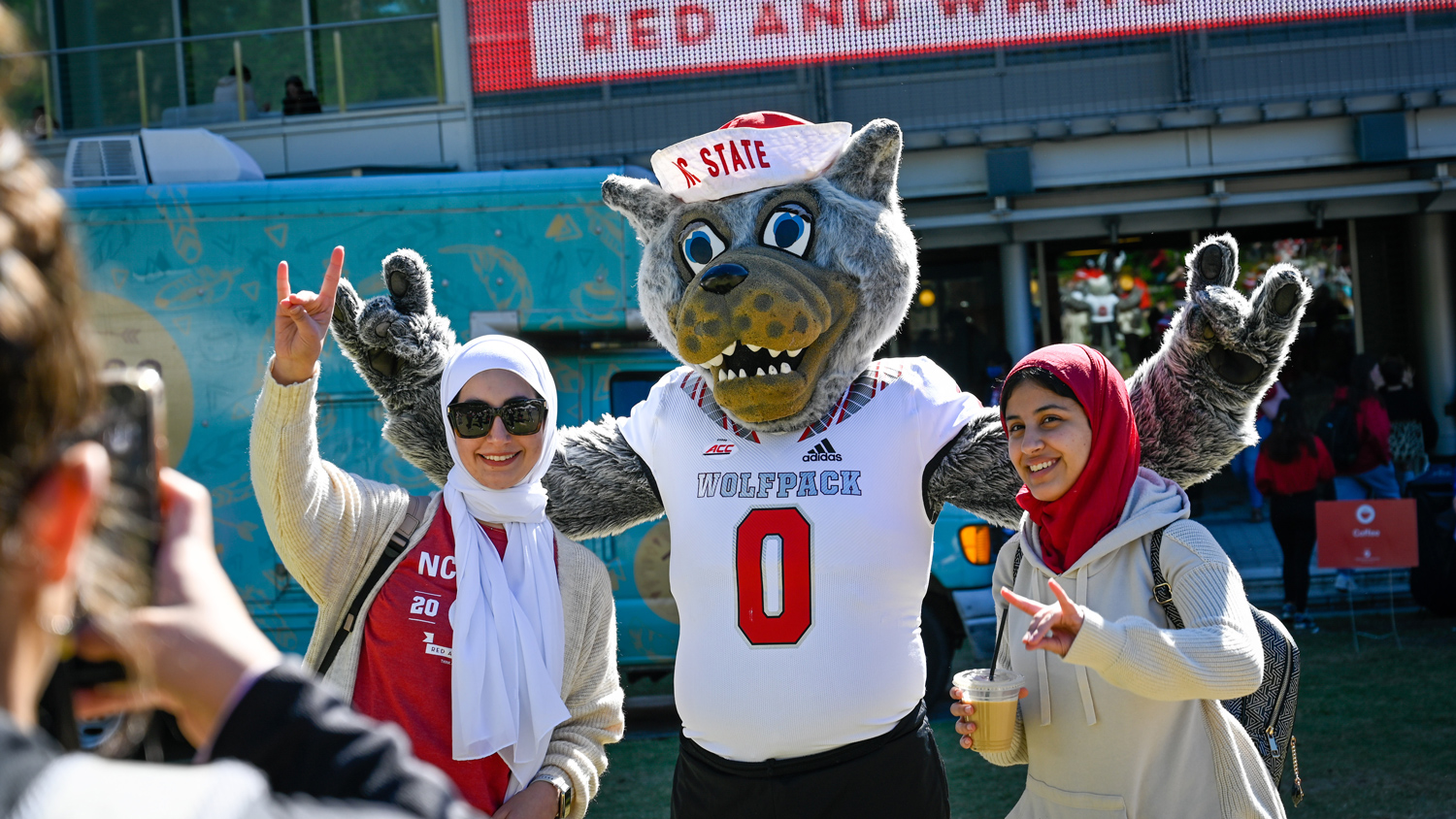 Mr. Wuf poses with two students.