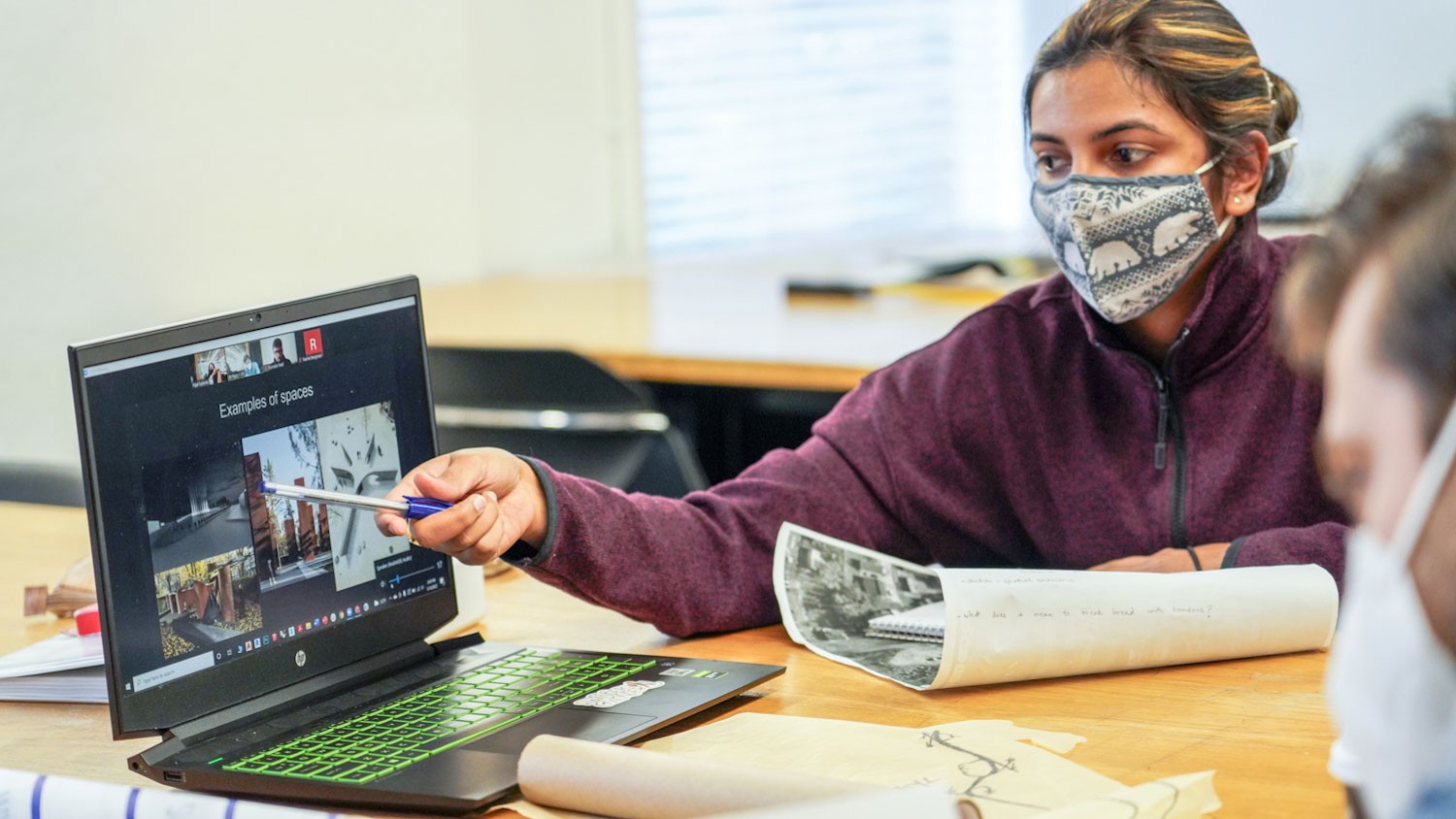 Students in face coverings looking at a computer