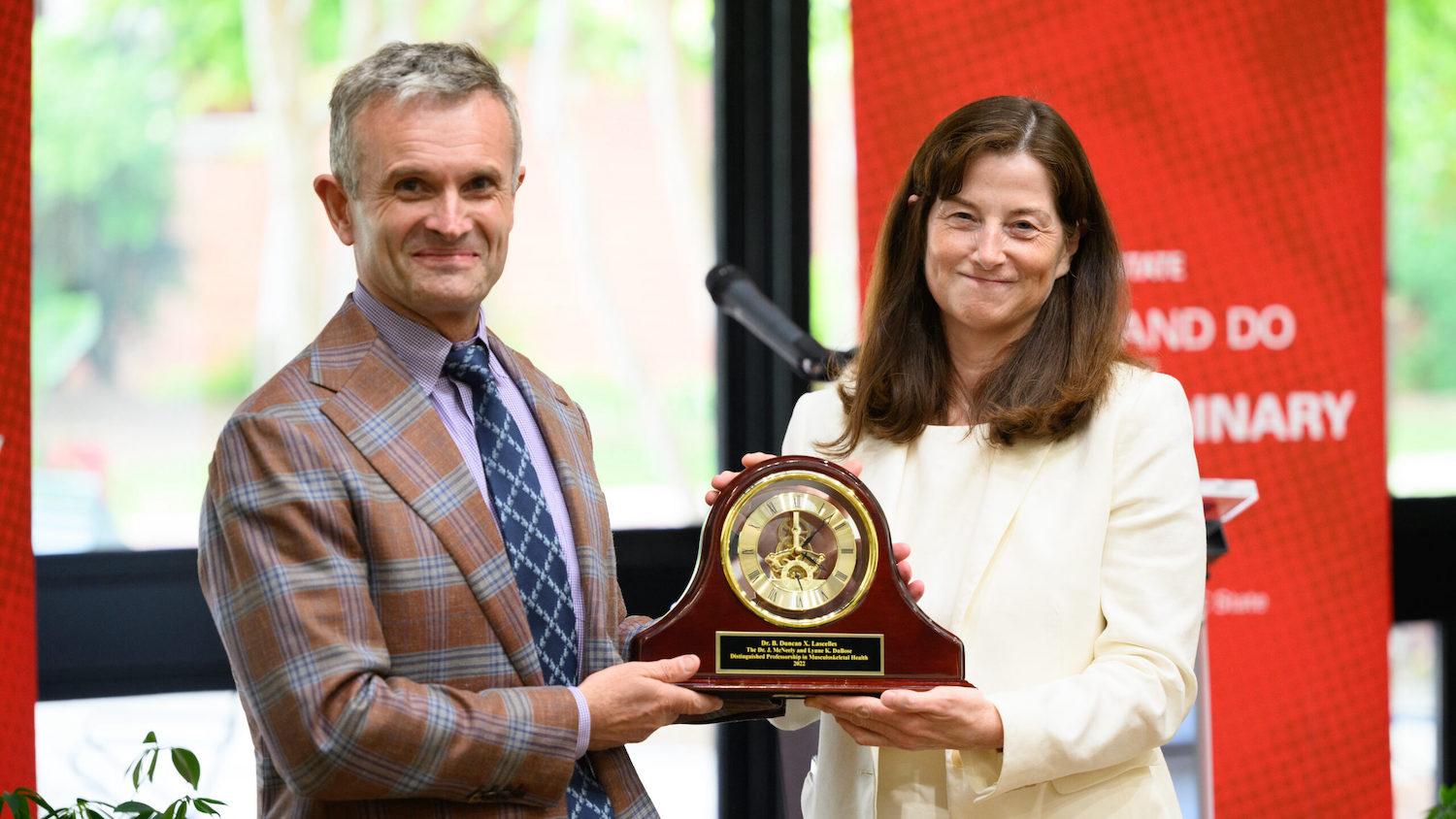 Duncan Lascelles receives a clock commemorating his appointment as a distinguished professor from CVM Dean Kate Meurs.