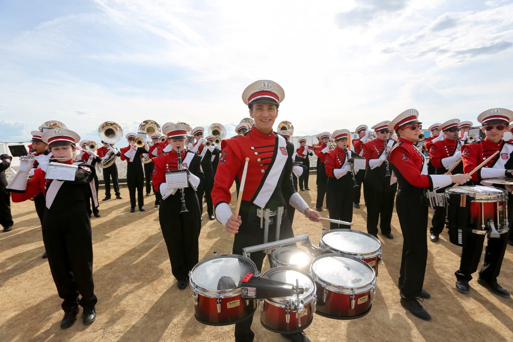 A student drummer standing amongst the marching band.