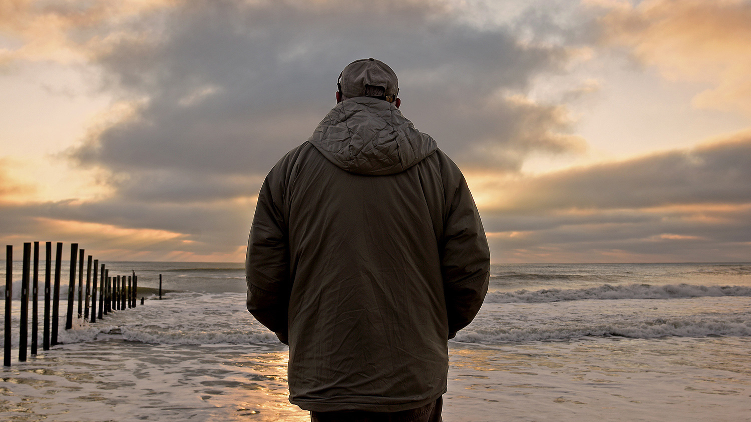 A man standing on the beach looking out at the ocean