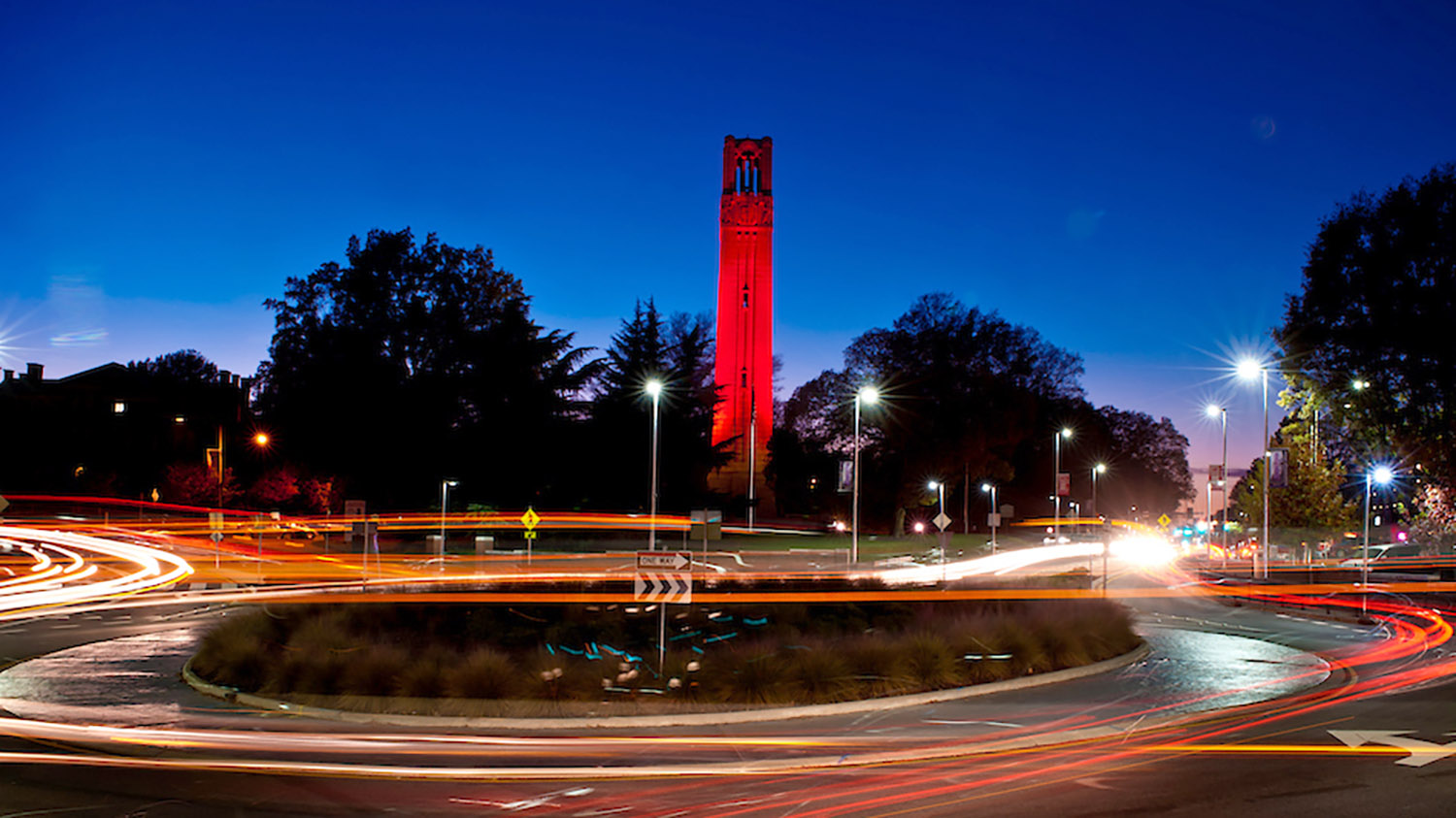 Cars driving by the Memorial Belltower at night