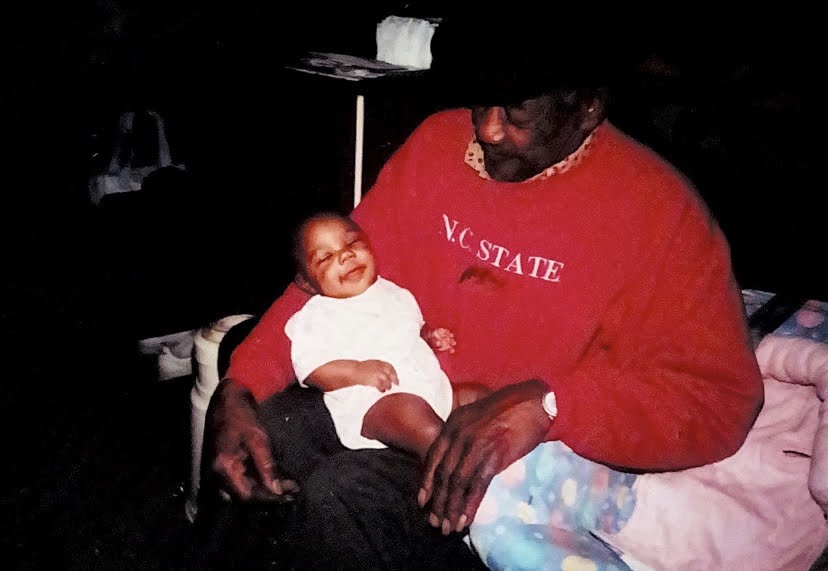 photo of Kacey Cooper as a baby being held by her grandfather, who wears an NC State sweatshirt