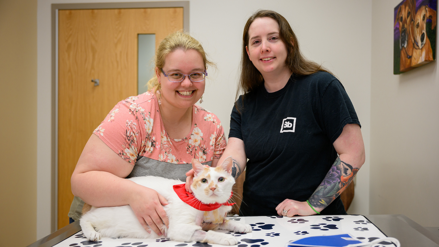 Bento poses with his owners, Jamie Caknipe and Kelly Gordon, during a visit to the NC State Veterinary Hospital.