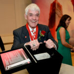 Tom Stafford smiling while holding a box containing a piece of granite from his beloved Memorial Belltower.