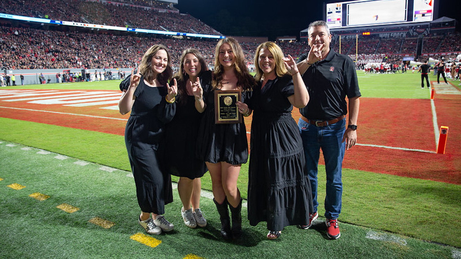 Meredith Gaskill (center) with her two sisters (left) and parents (right) on the field at Carter-Finley Stadium