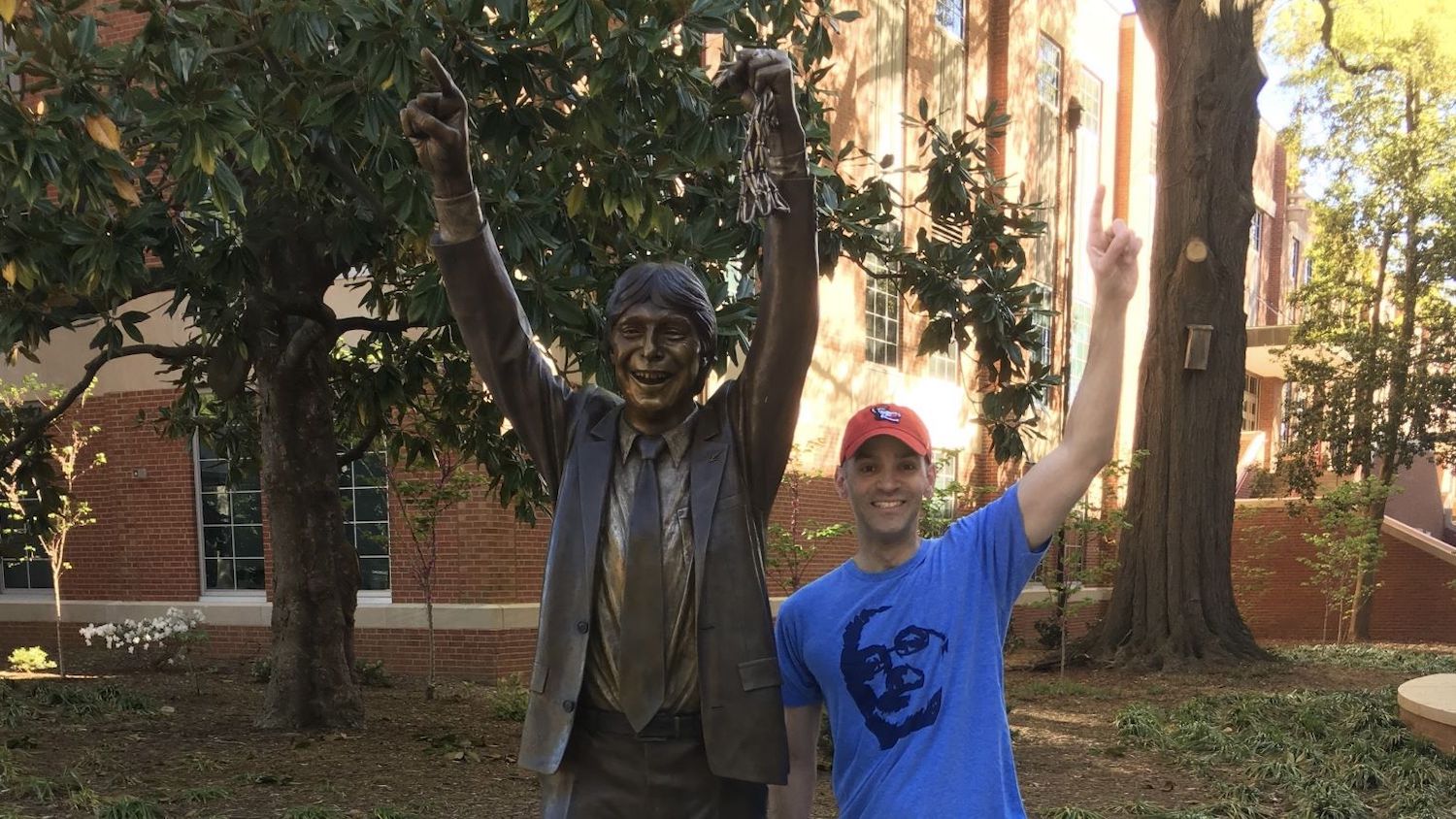 Lope “Max” Diaz II standing next to a statue of Jim Valvano.