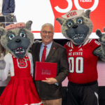 Chancellor Randy Woodson presents Mr. and Ms. Wuf with their honorary Pullen Society induction certificate.