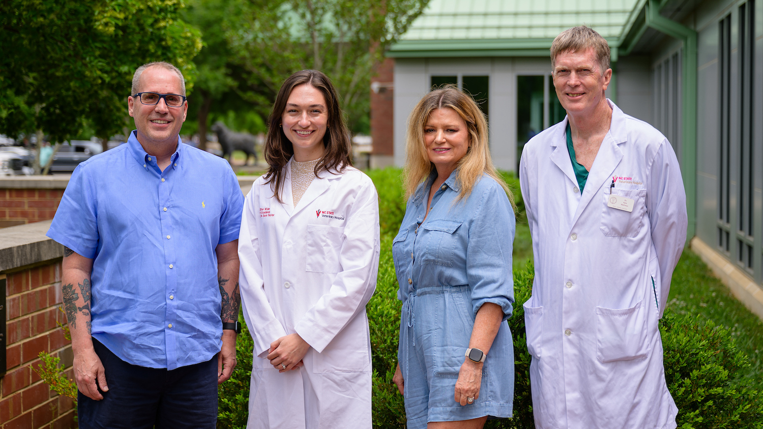 Proudly wearing her Olive Wilder Coat of Excellence, small animal surgery resident Dr. Sarah Saylor stands between Tom and Tonya Wilder and alongside Dr. Kyle Mathews, a professor of soft tissue and oncologic surgery. (John Joyner/NC State College of Veterinary Medicine)