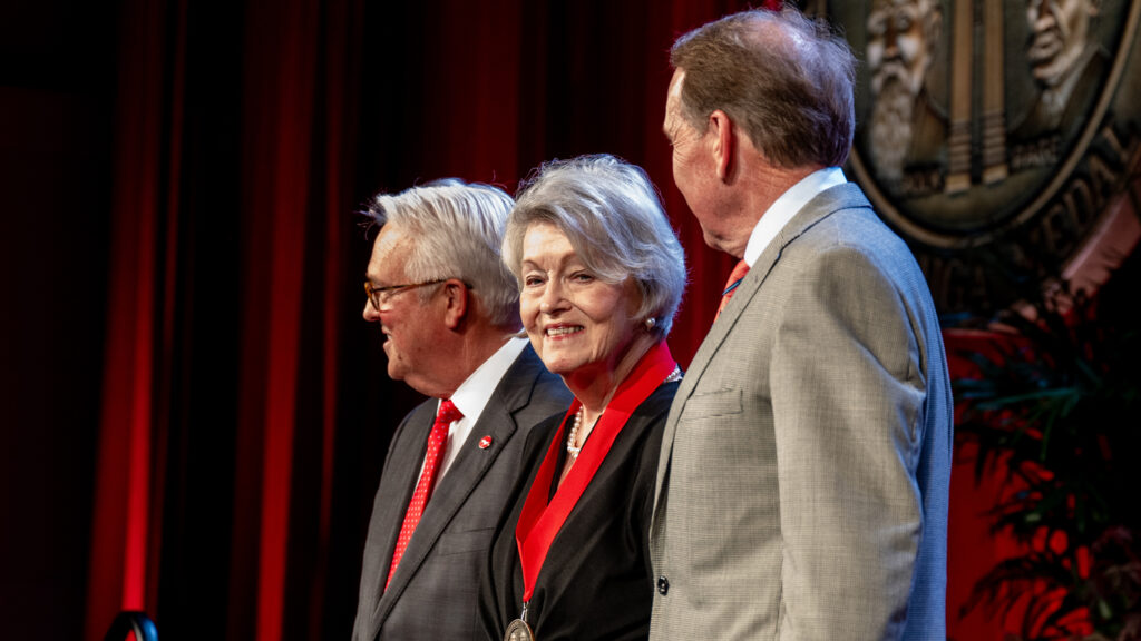 Ann Goodnight stands on stage with Chancellor Randy Woodson (left) and Ed Weisiger Jr. following her receipt of the Watauga Medal.