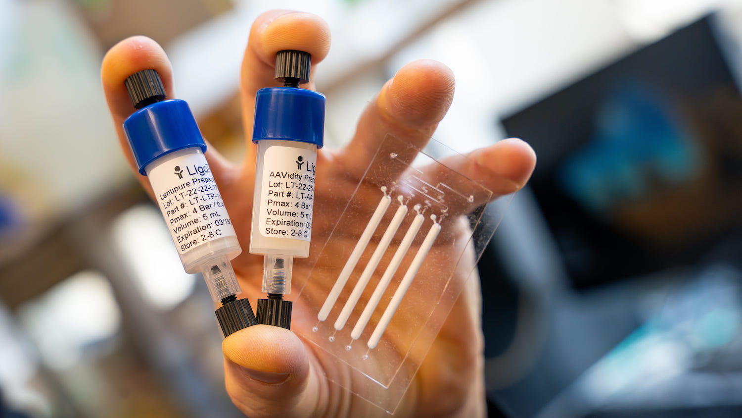 A hand holding vials in a lab