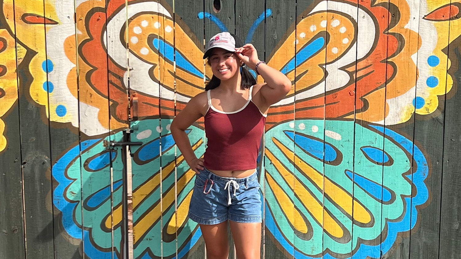 First-generation student and nutrition science major Anna Shore standing in front of a butterfly mural