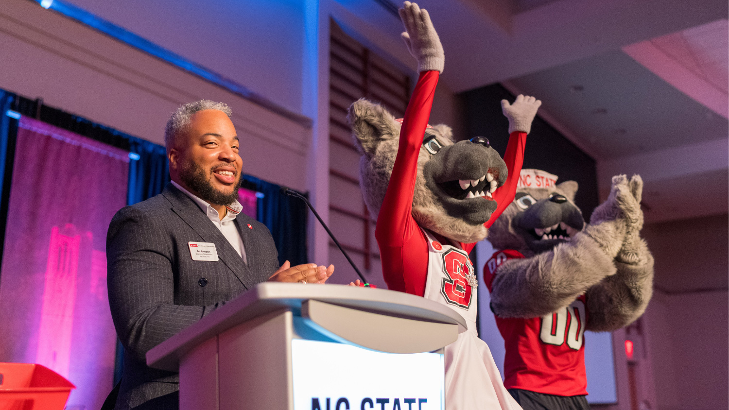 Jay Arrington, director of admissions for the Jenkins MAC Program, speaks at the 30th anniversary celebration while Ms. and Mr. Wuf cheer him on. (Photo by Justin Kase Conder)