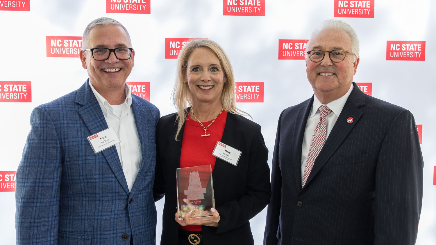 Mary Fedewa '91 — flanked by Poole College Dean Frank Buckless (L) and NC State Chancellor Randy Woodson (R) — holding Poole College’s 2024 Distinguished Alumni Award.