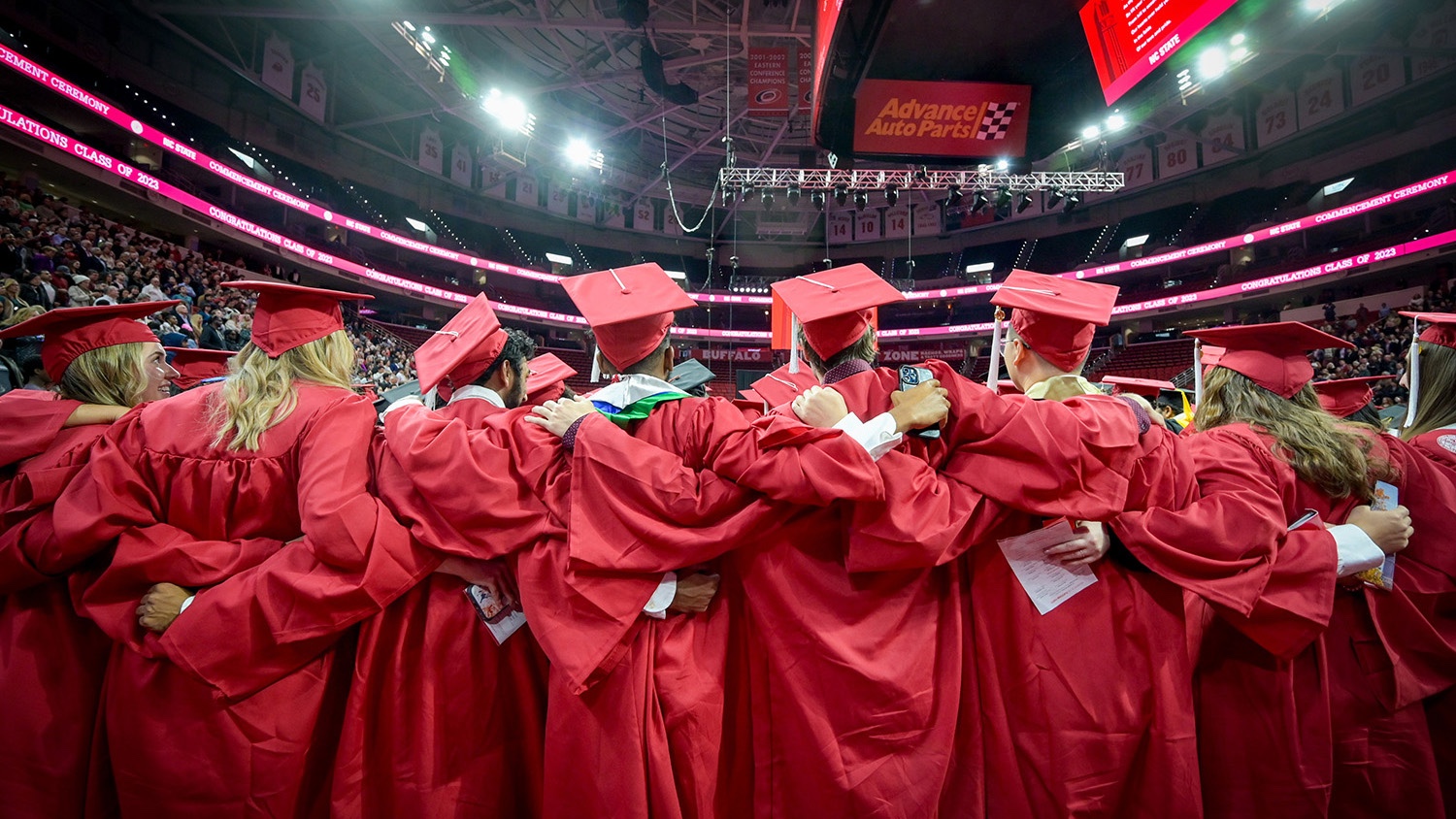 Graduates with their arms around each other at convocation in PNC Arena