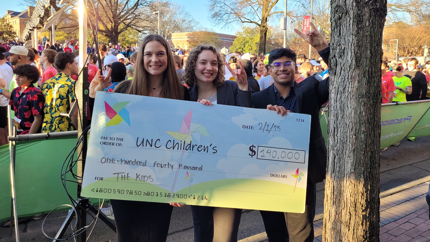 Three Park Scholars holding a ceremonial check made out to the UNC Children's Hospital during the 2025 Krispy Kreme Challenge