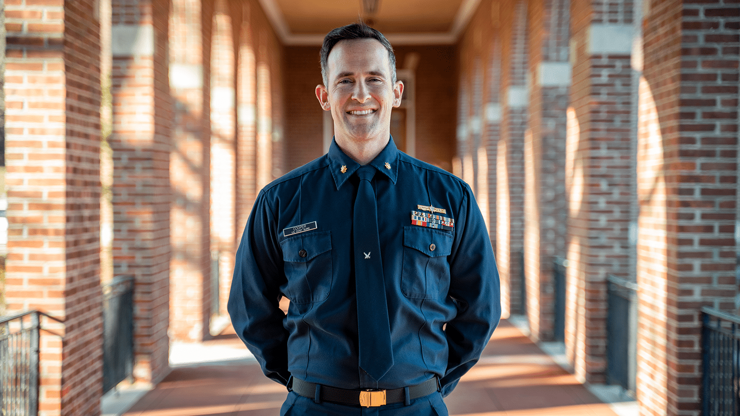 Cameron Cooper standing in his Coast Guard uniform with his arms behind his back.