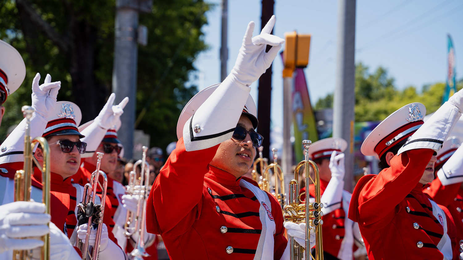 Members of the NC State Marching Band hold up the wolfie hand sign