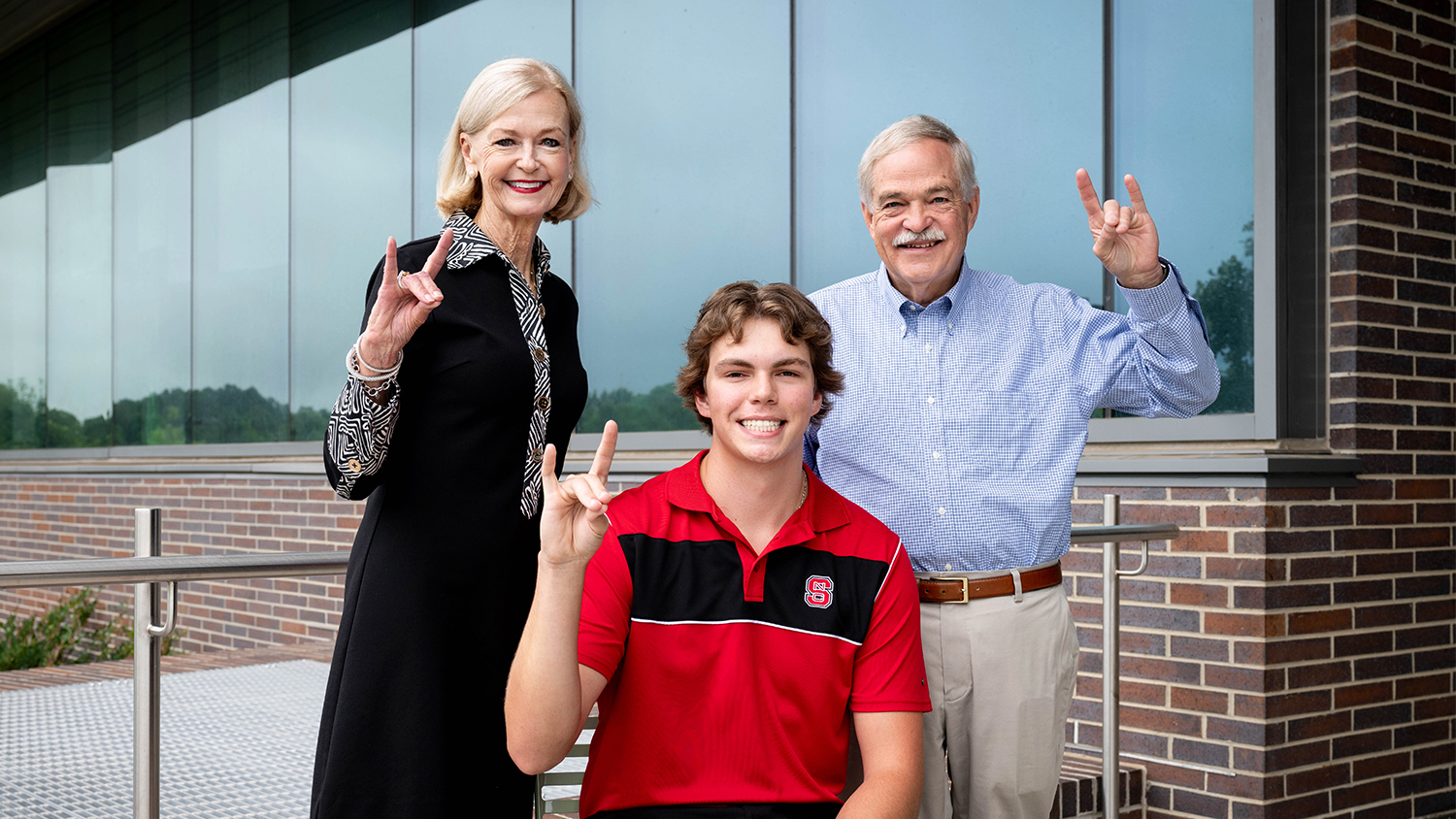 From left: Barbara Pleasant, Braydon Boaz and Dan Pleasant holding up the wolfie hand sign.